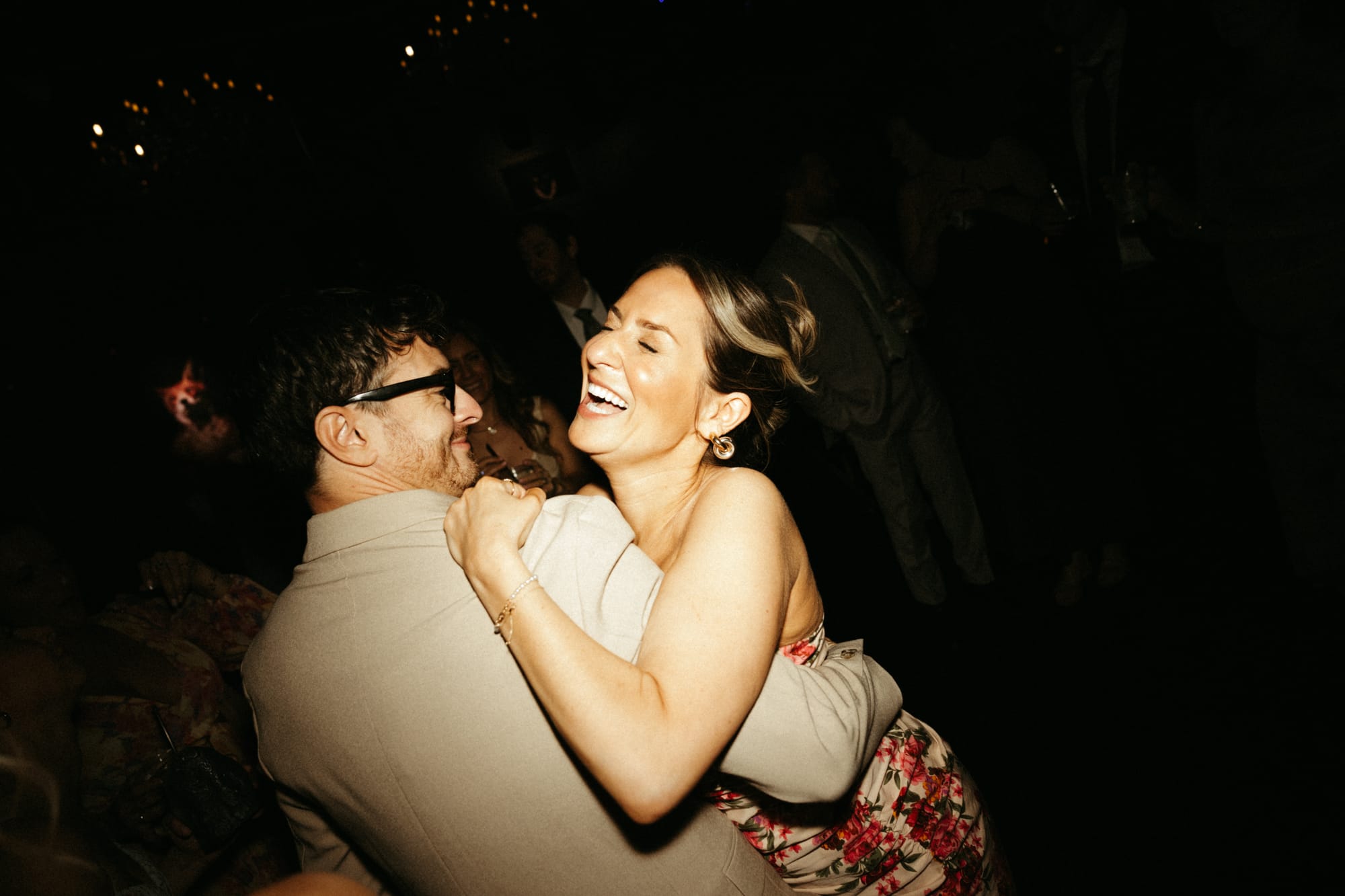 Wedding guests celebrating on a packed dance floor late at night